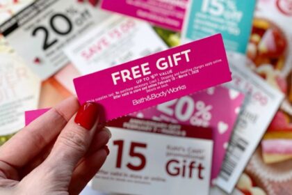 woman with red nails holding coupon for a free gift above various other coupons